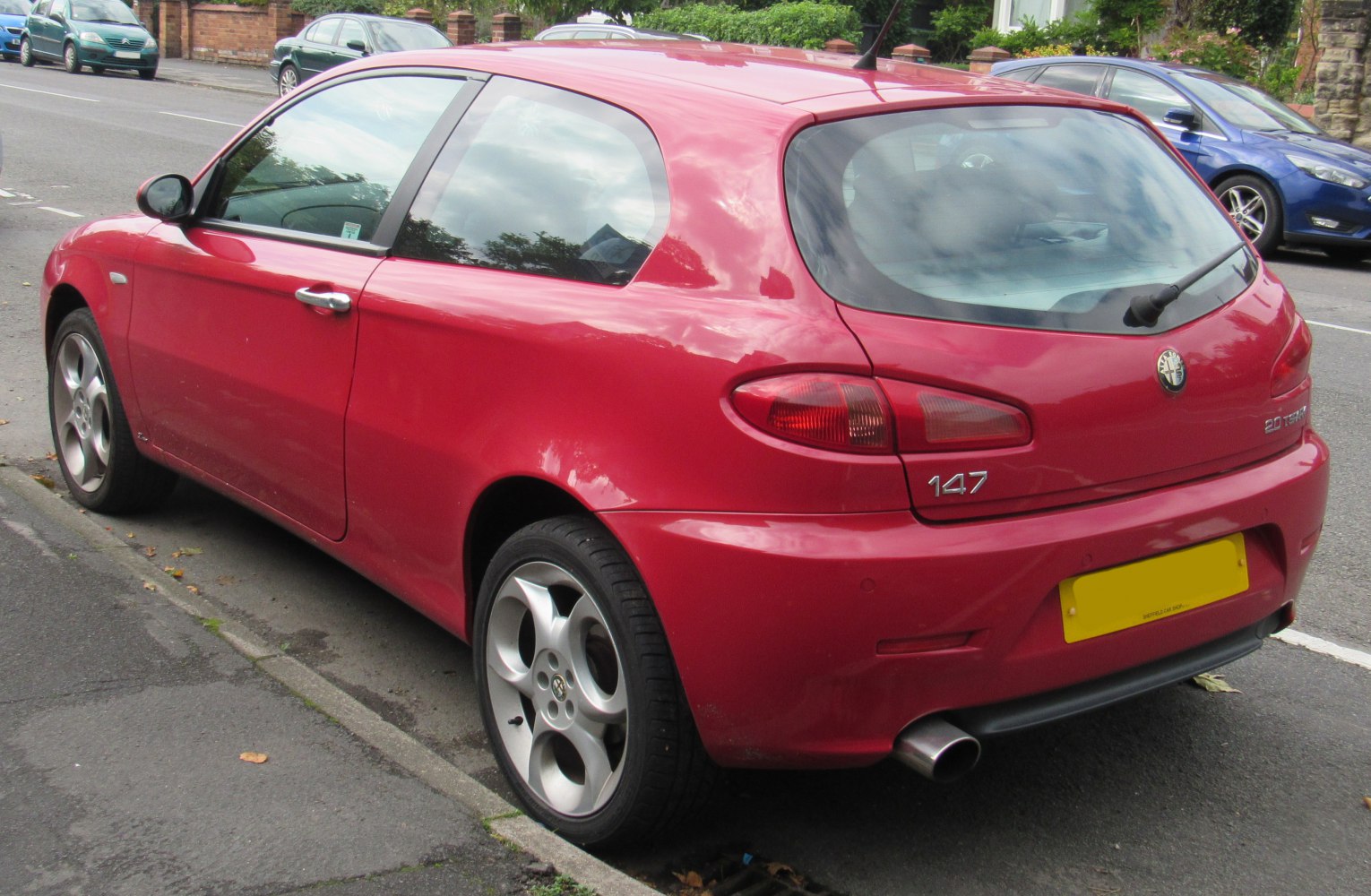 Red 3-door hatchback rear view with distinctive taillights and alloy wheels