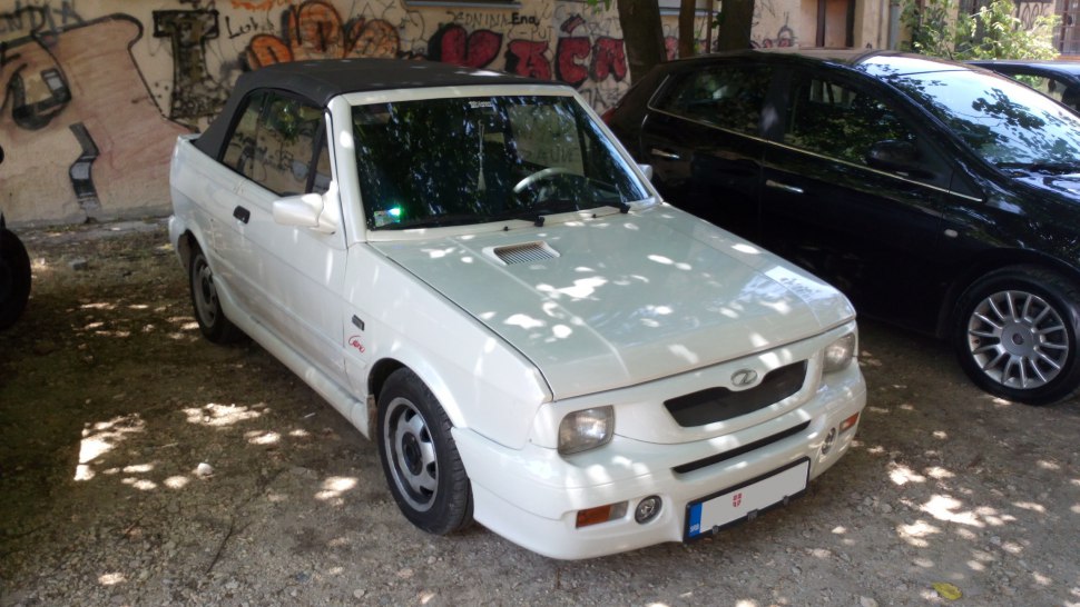 White compact convertible with soft top and distinctive front grille.