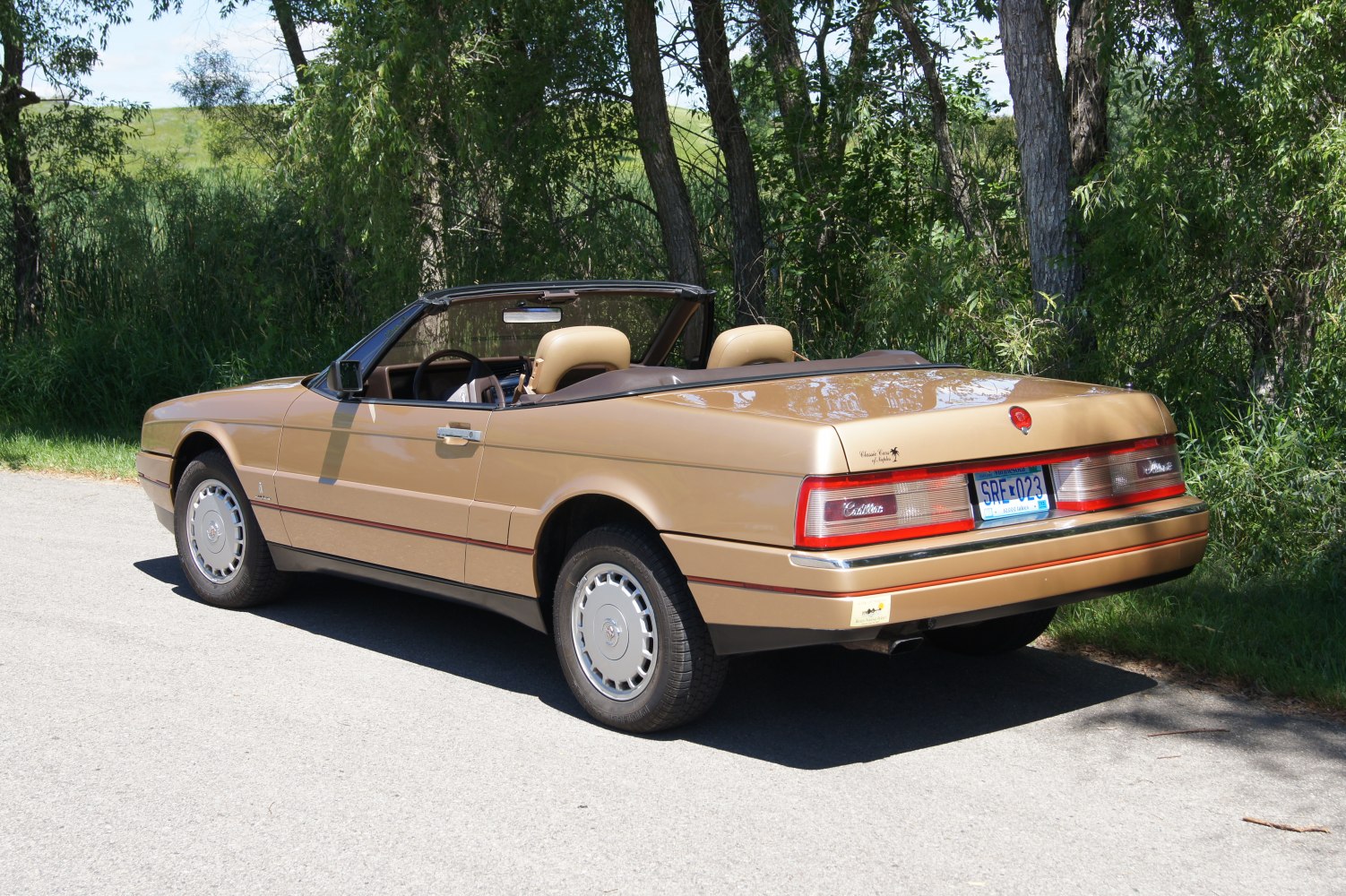 Rear side view of a 1990 convertible luxury coupe with classic wheels
