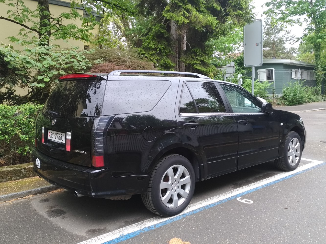 Rear side view of black SUV with roof rails and vertical taillights