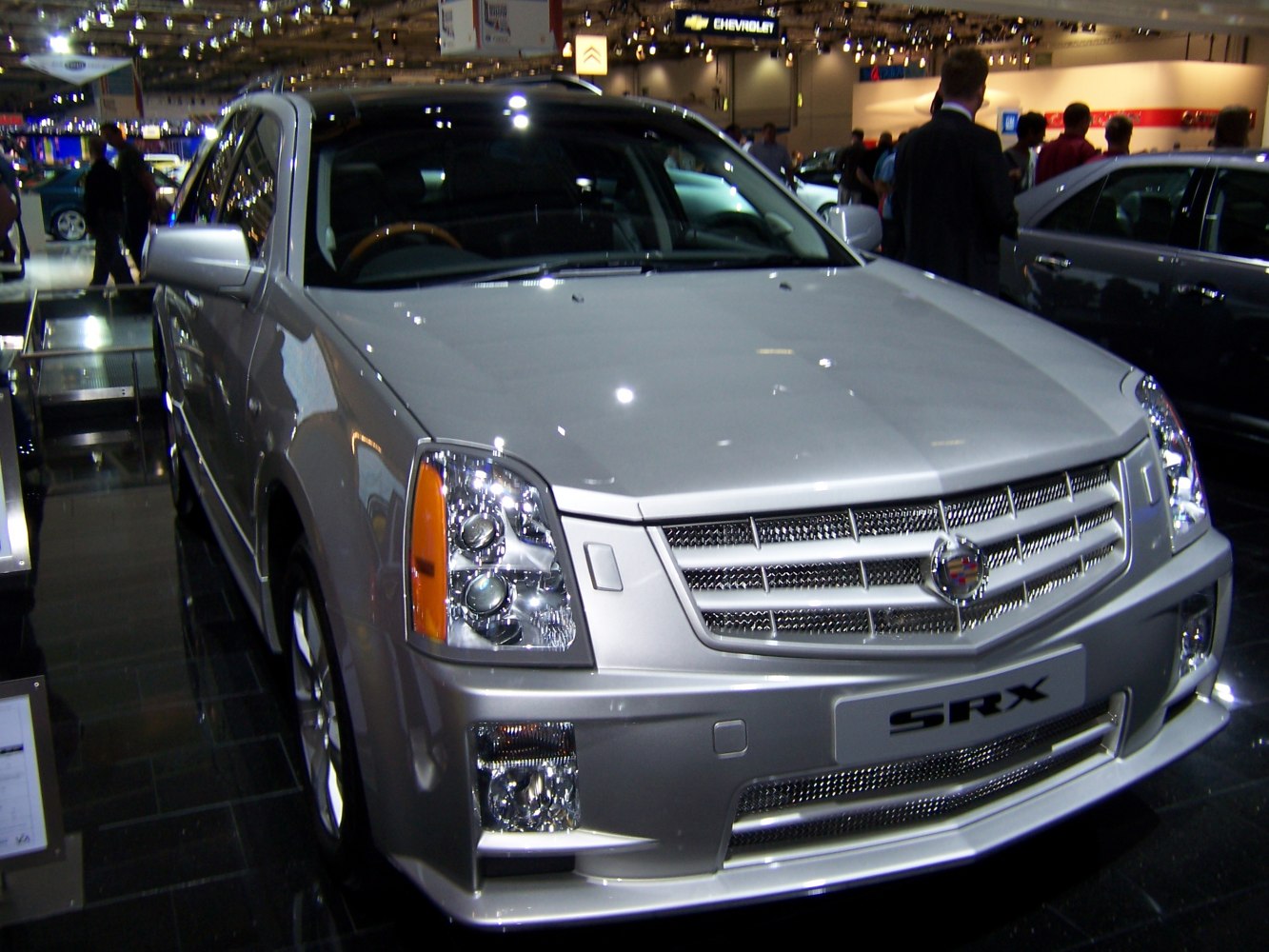Front grille and dual projector headlights with fog lights on a silver SUV.