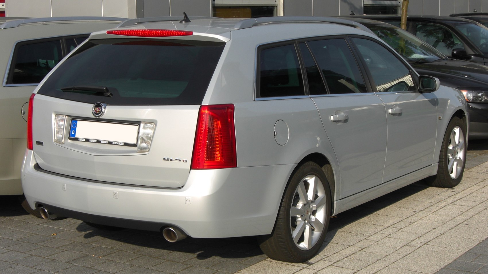 Rear and side view of a silver station wagon with dual exhaust and roof rails.