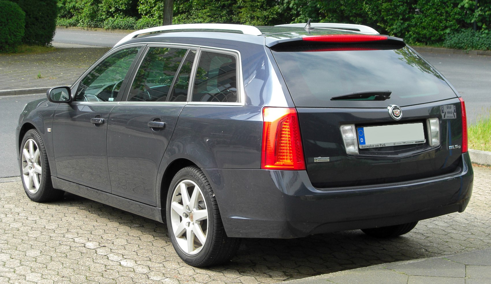 Rear side view of wagon with vertical taillights, alloy wheels, and roof rails