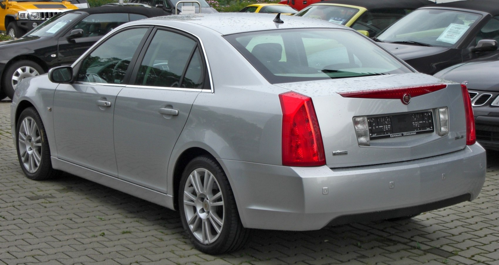 Silver sedan rear with vertical red taillights and multi-spoke alloy wheels