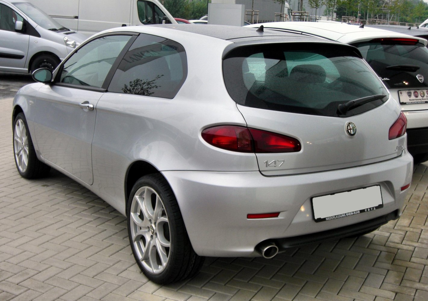 Rear-side view of a silver 3-door hatchback with unique oval tail lights