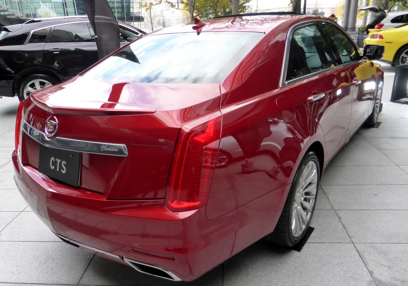 Rear view of a red luxury sedan with vertical tail lights and trunk spoiler