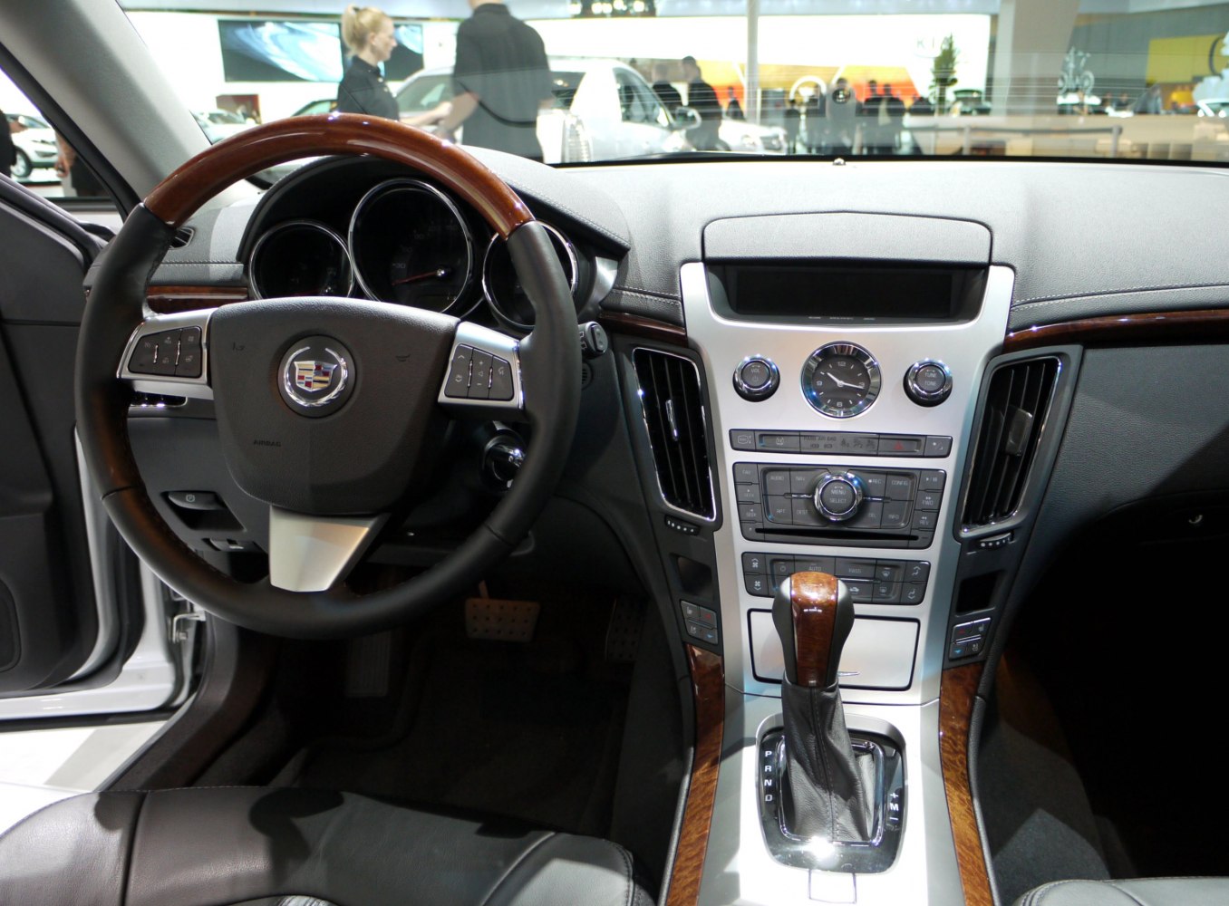 Wood-trimmed steering wheel and analog clock on luxury car dashboard
