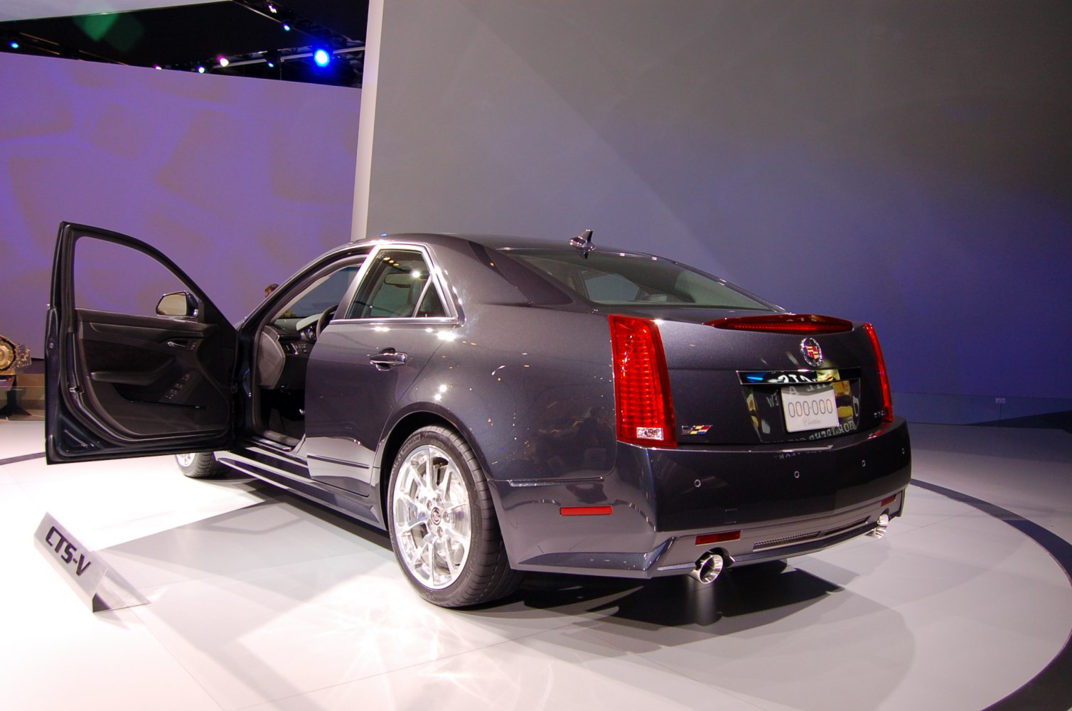 Rear side view with open driver door, distinctive tail lights, and sporty dual exhaust.