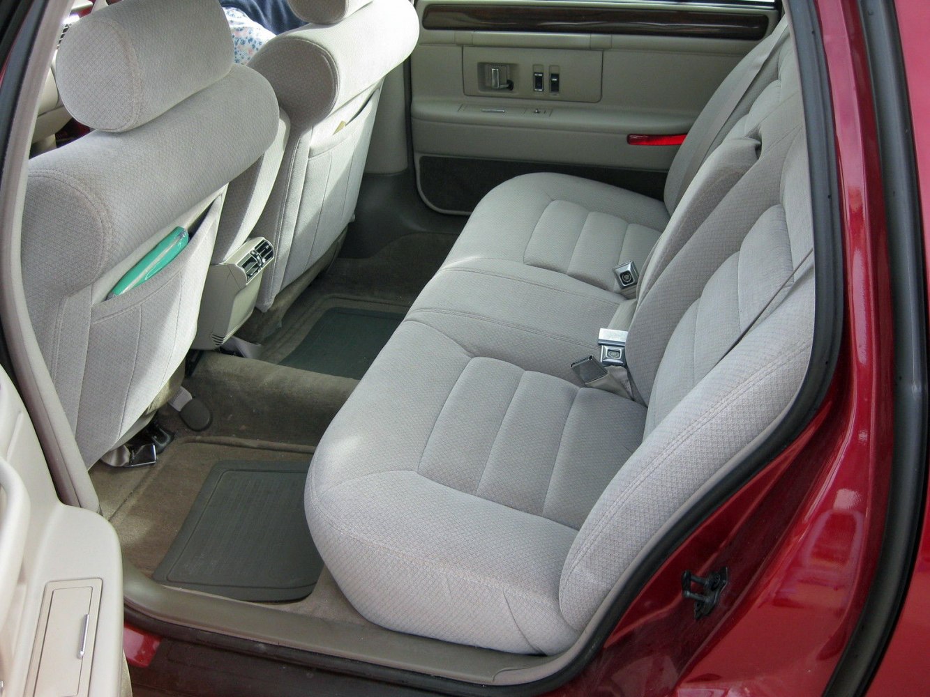Rear car seat upholstery with headrests, door panel controls, and floor mats