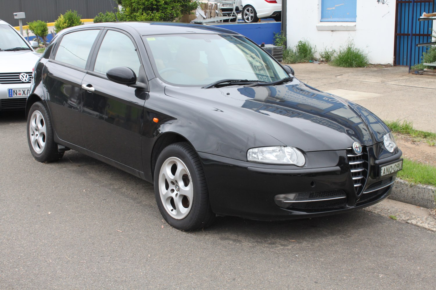 Black 5-door hatchback front side with distinctive Alfa Romeo grille and alloy wheels