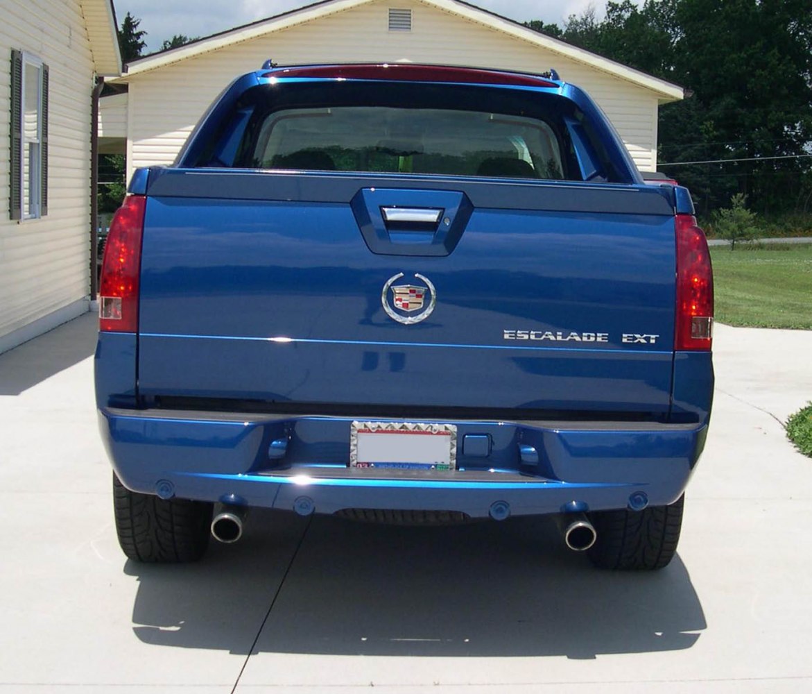 Rear view of a pickup tailgate with dual exhausts and emblem