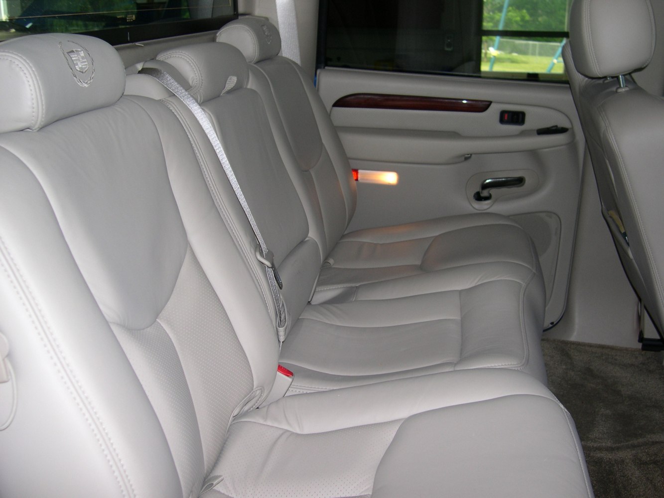 Light gray leather rear seats with embroidered headrests and wood trim on door panel