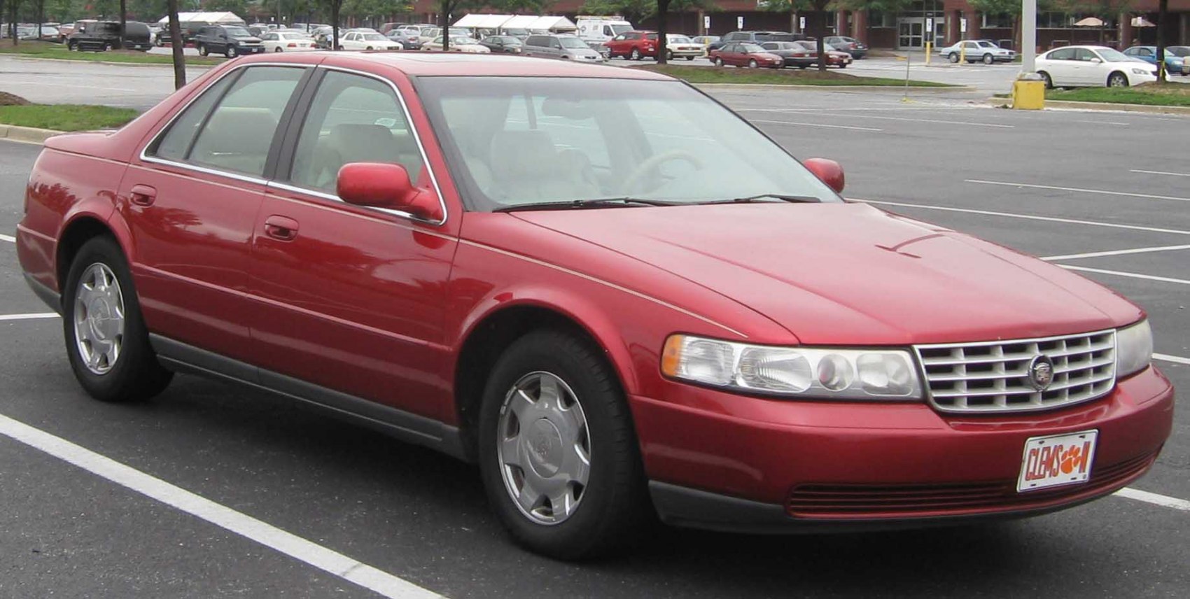 Red luxury sedan with chrome grille and alloy wheels in a parking lot