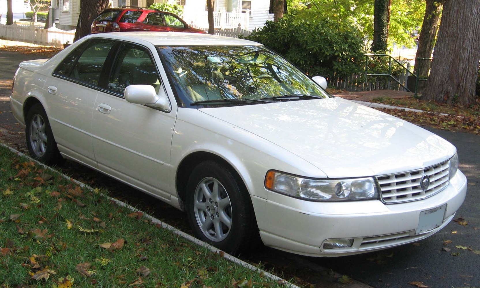 White full-size sedan showing front side, grille, headlights, and alloy wheels