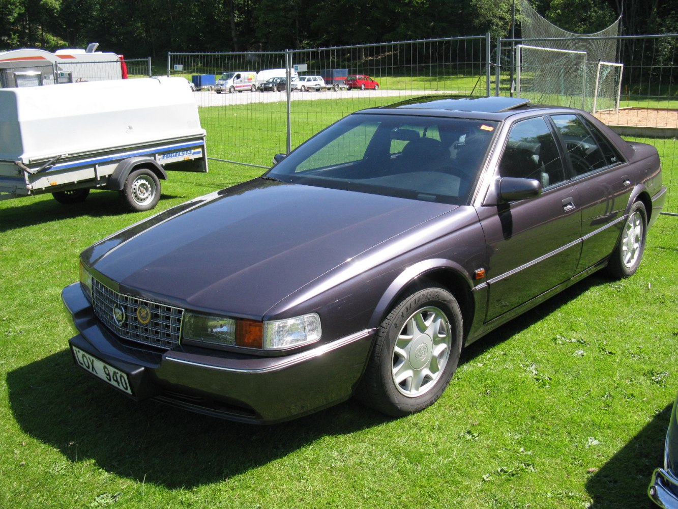 Luxury sedan with sunroof and alloy wheels on grass.