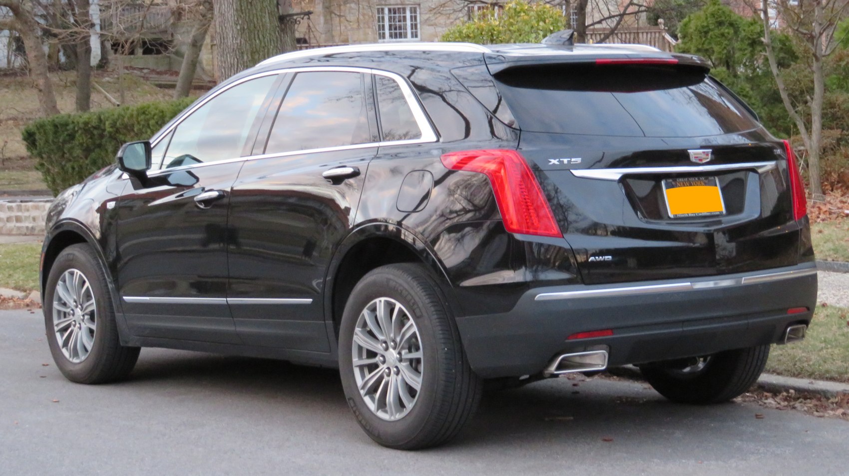Black mid-size luxury SUV rear side with dual exhausts and chrome accents