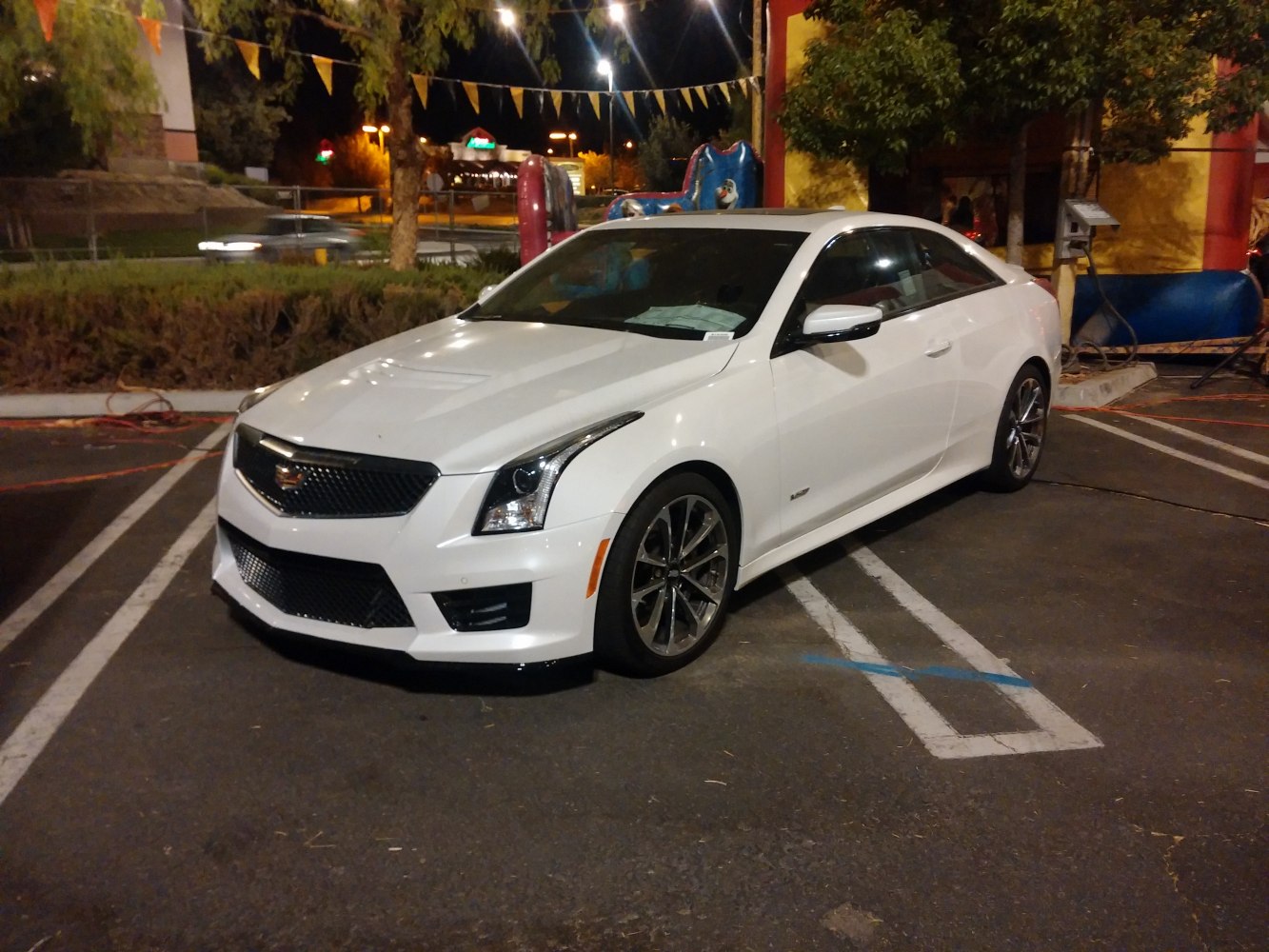 White coupe with sharp front grille and sleek body shape at night