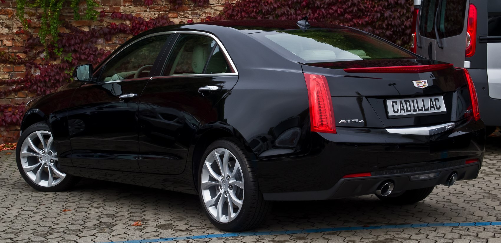 Rear side view of black sedan with dual exhaust and distinct tail lights