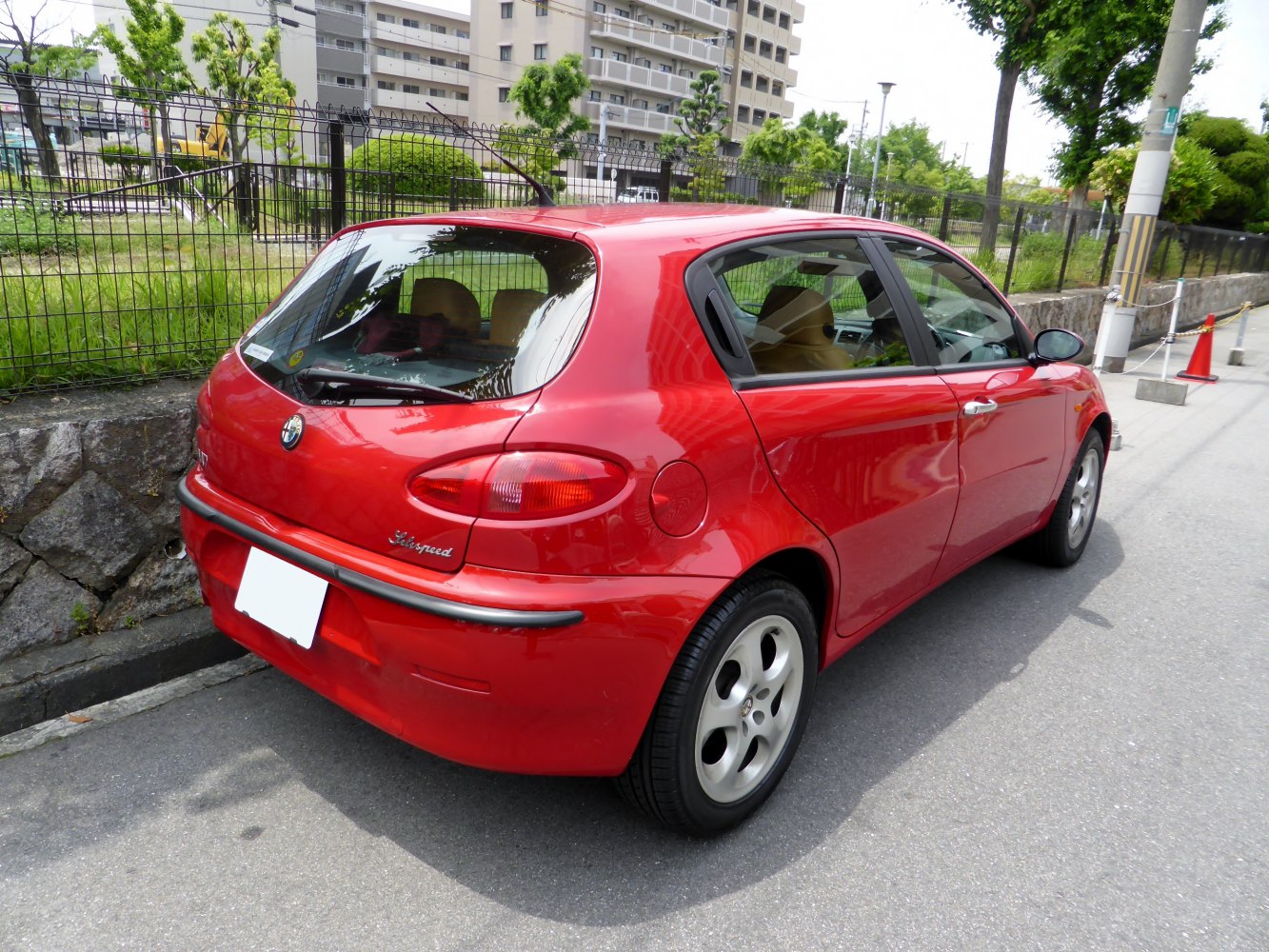 Red 5-door hatchback rear view with round taillights and alloy wheels