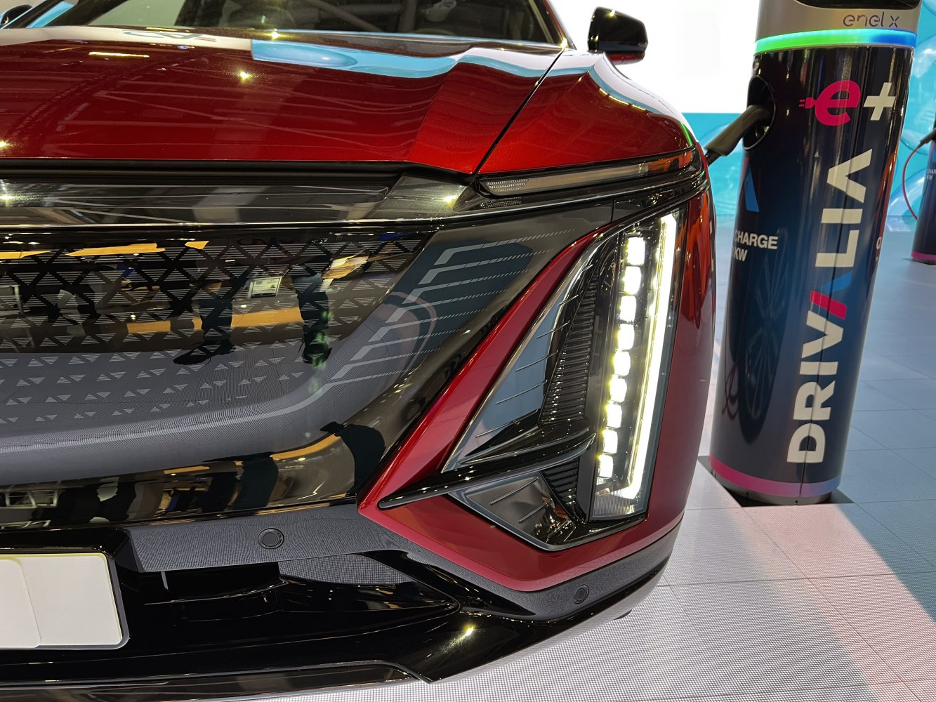 Close-up of futuristic front LED headlight and nearby EV charging station.