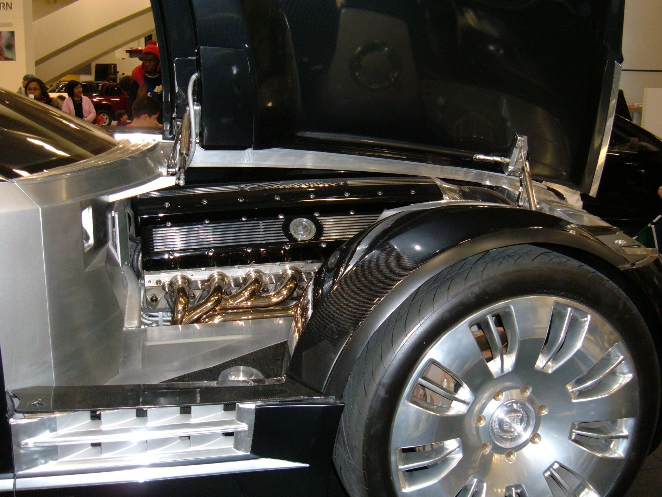 Close-up of V16 engine and front wheel with exhaust headers and alloy rim