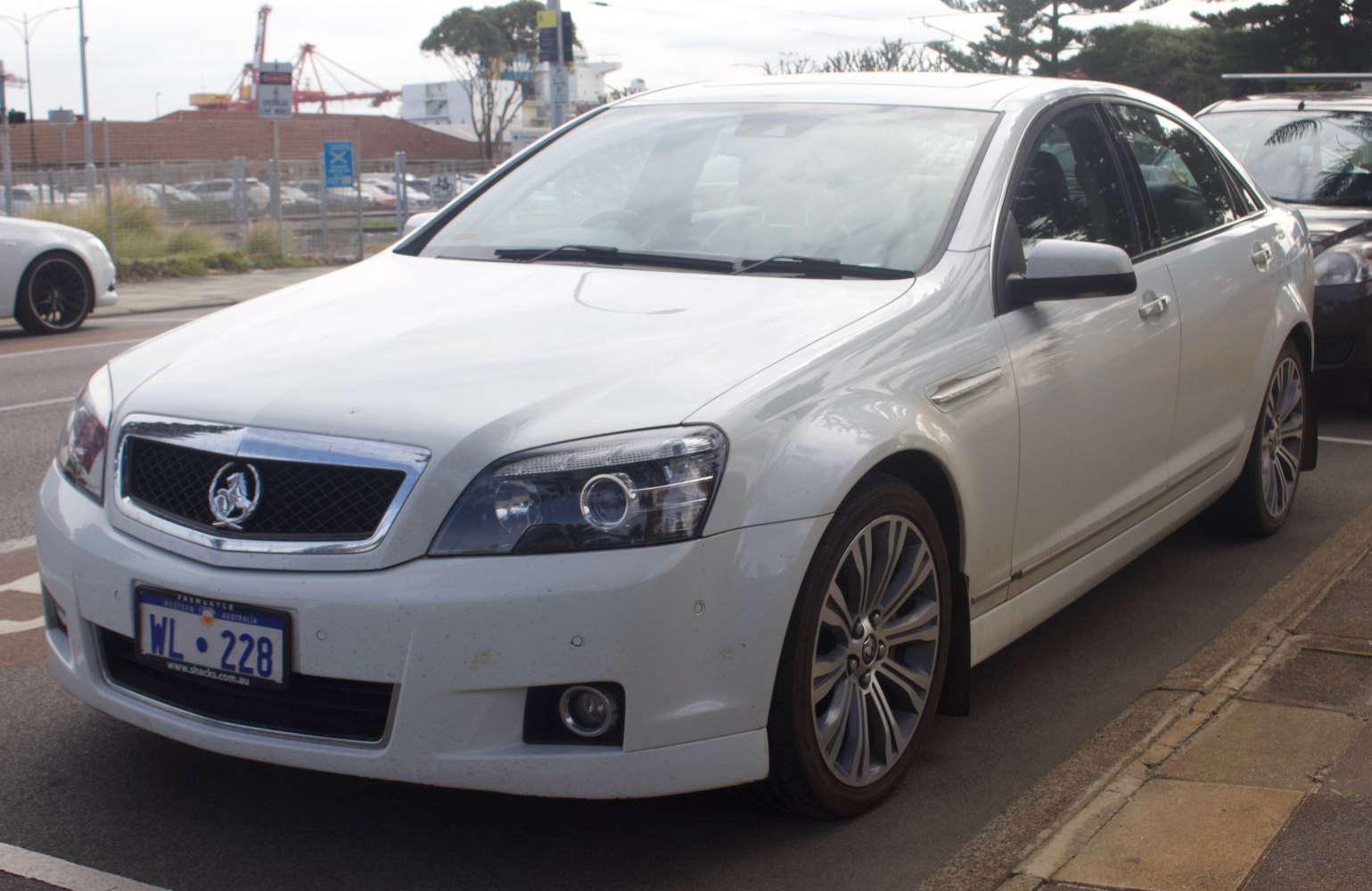 White sedan with chrome grille and alloy wheels parked on street