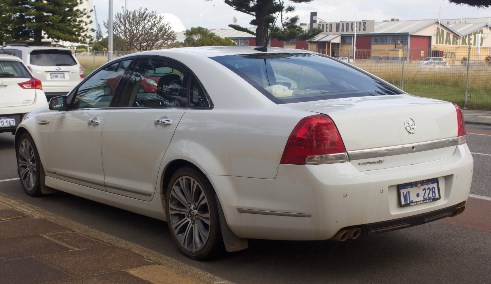 White sedan rear side with alloy wheels and dual exhaust
