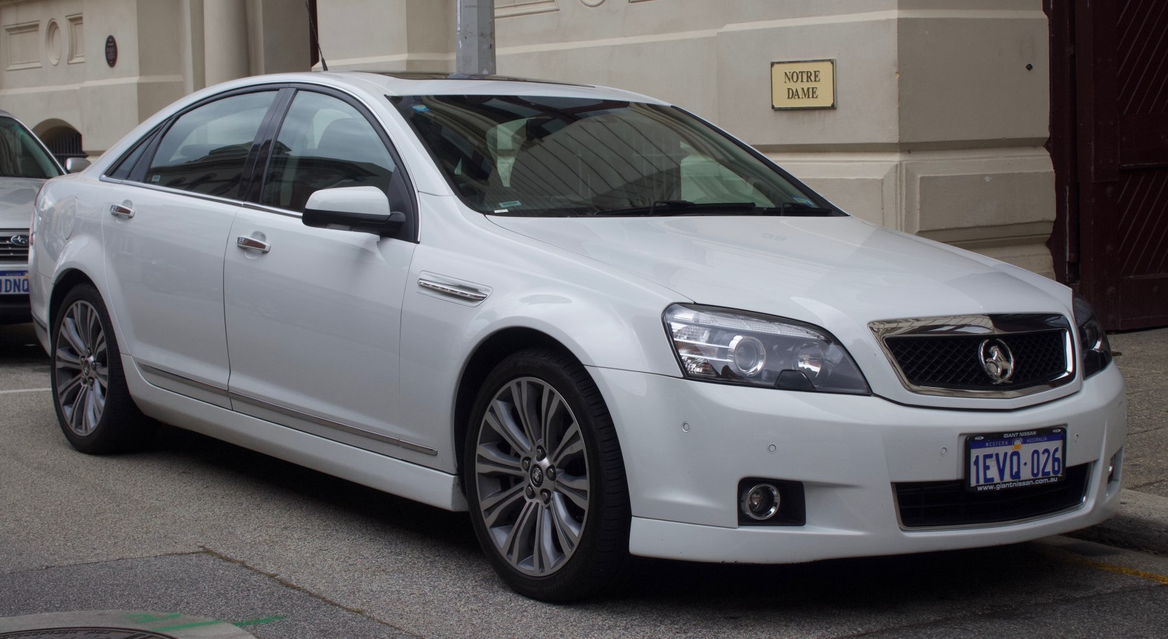 White sedan with distinctive headlamps and multi-spoke alloy wheels.