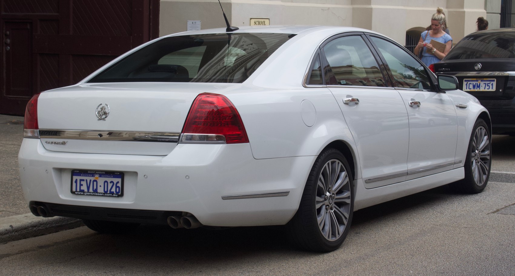 White luxury sedan rear with quad exhaust and LED taillights