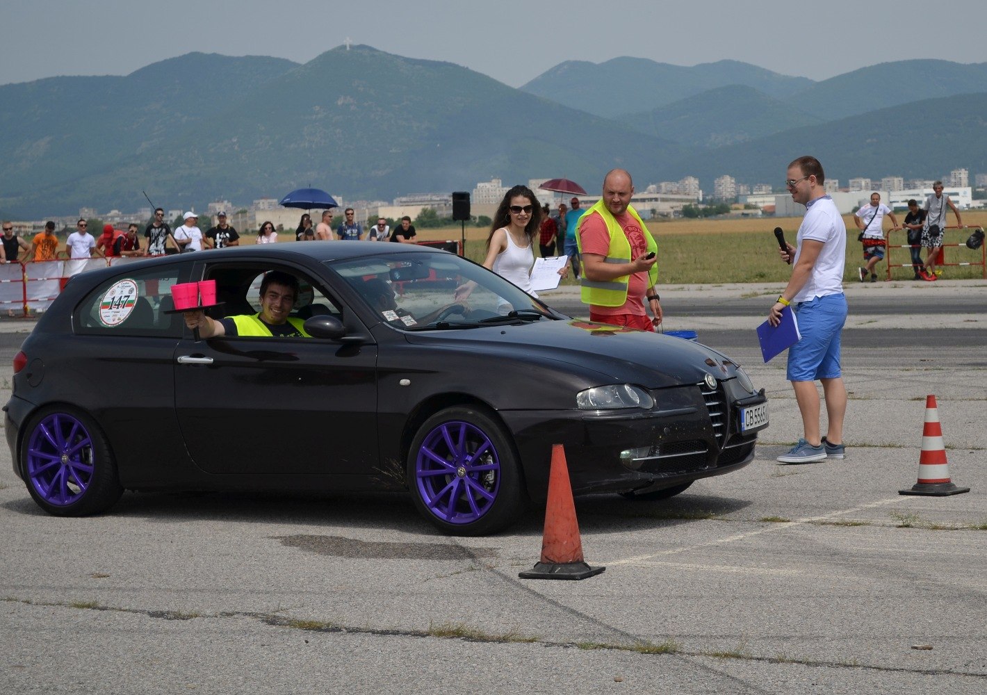 Black 3-door hatchback with purple wheels at outdoor event
