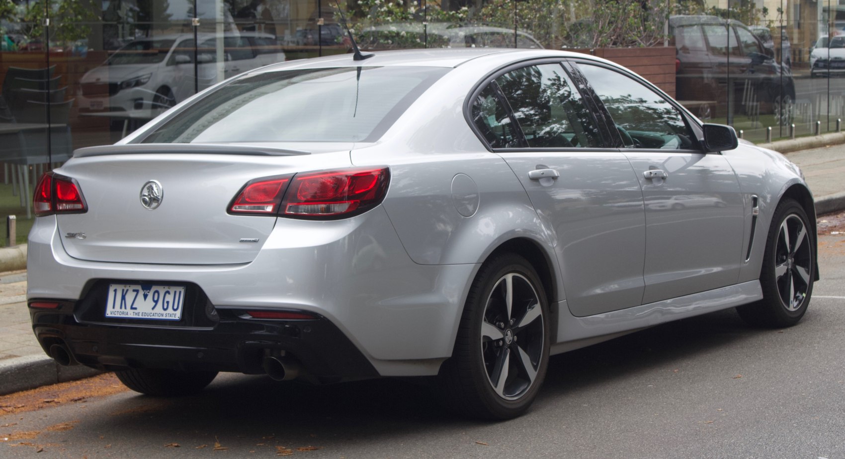 Rear view of silver sports sedan with spoiler and dual exhausts
