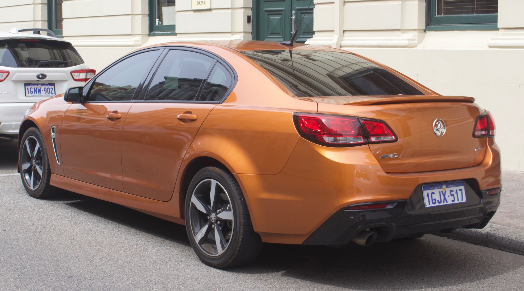 Orange sedan rear and side view with taillights and alloy wheels.