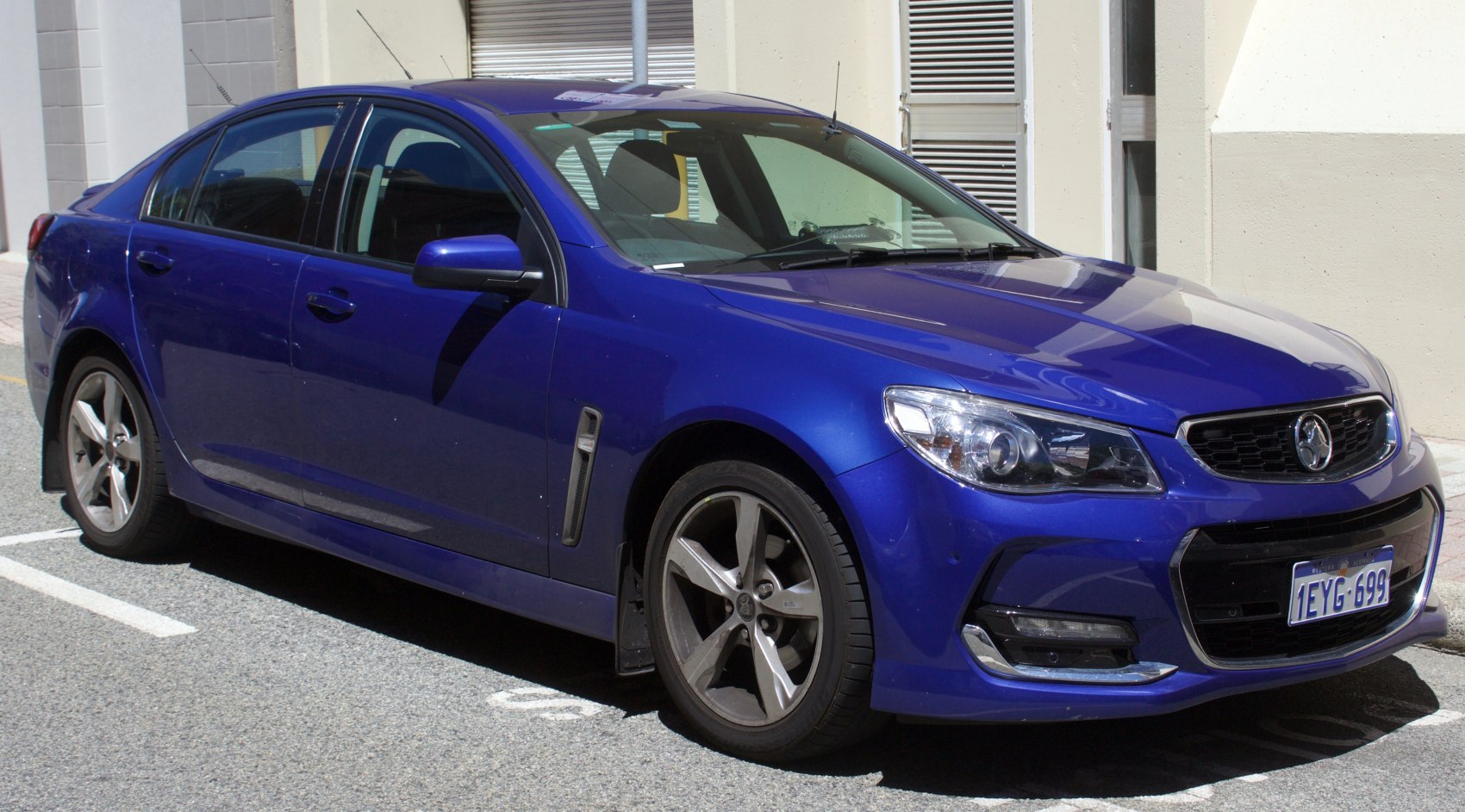 Front-side view of blue four-door sedan with distinct headlights and alloy wheels