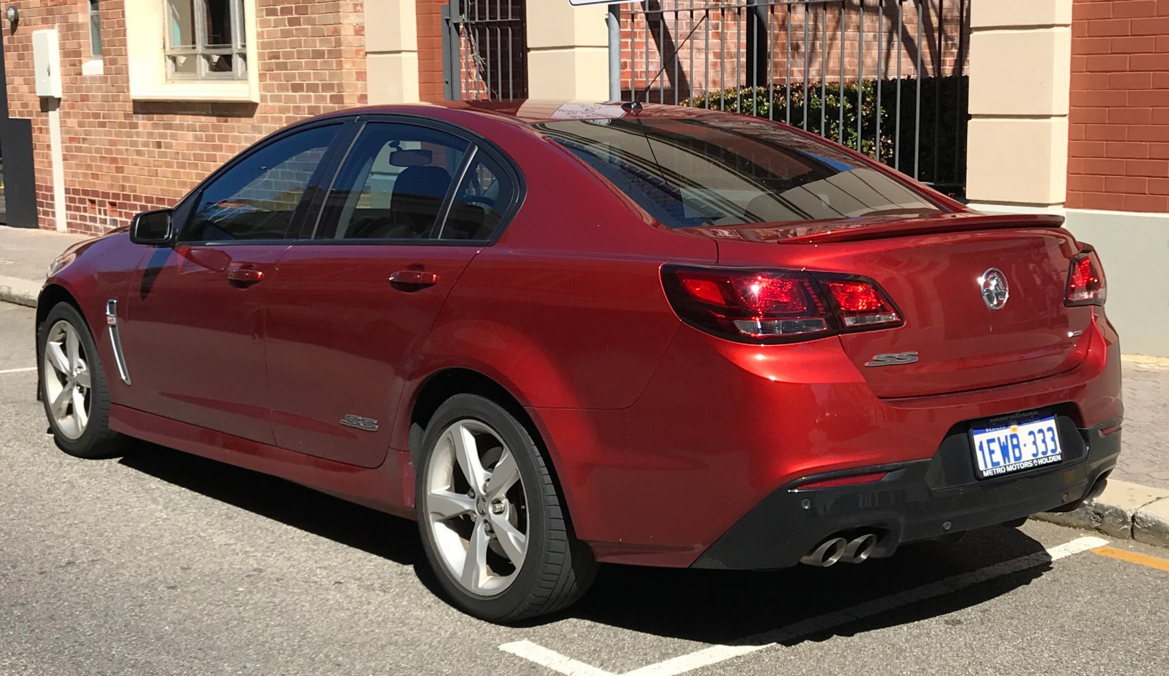 Red mid-size sedan rear side with sporty SS trim and dual exhausts