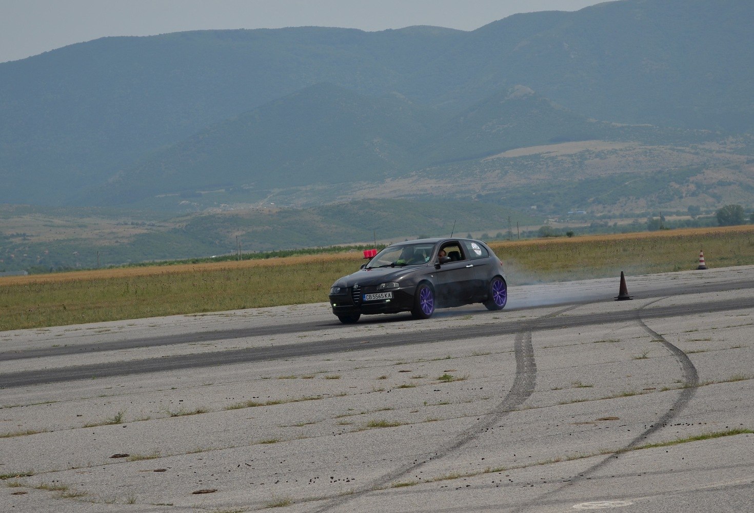 3-door hatchback drifting with purple wheels on asphalt track