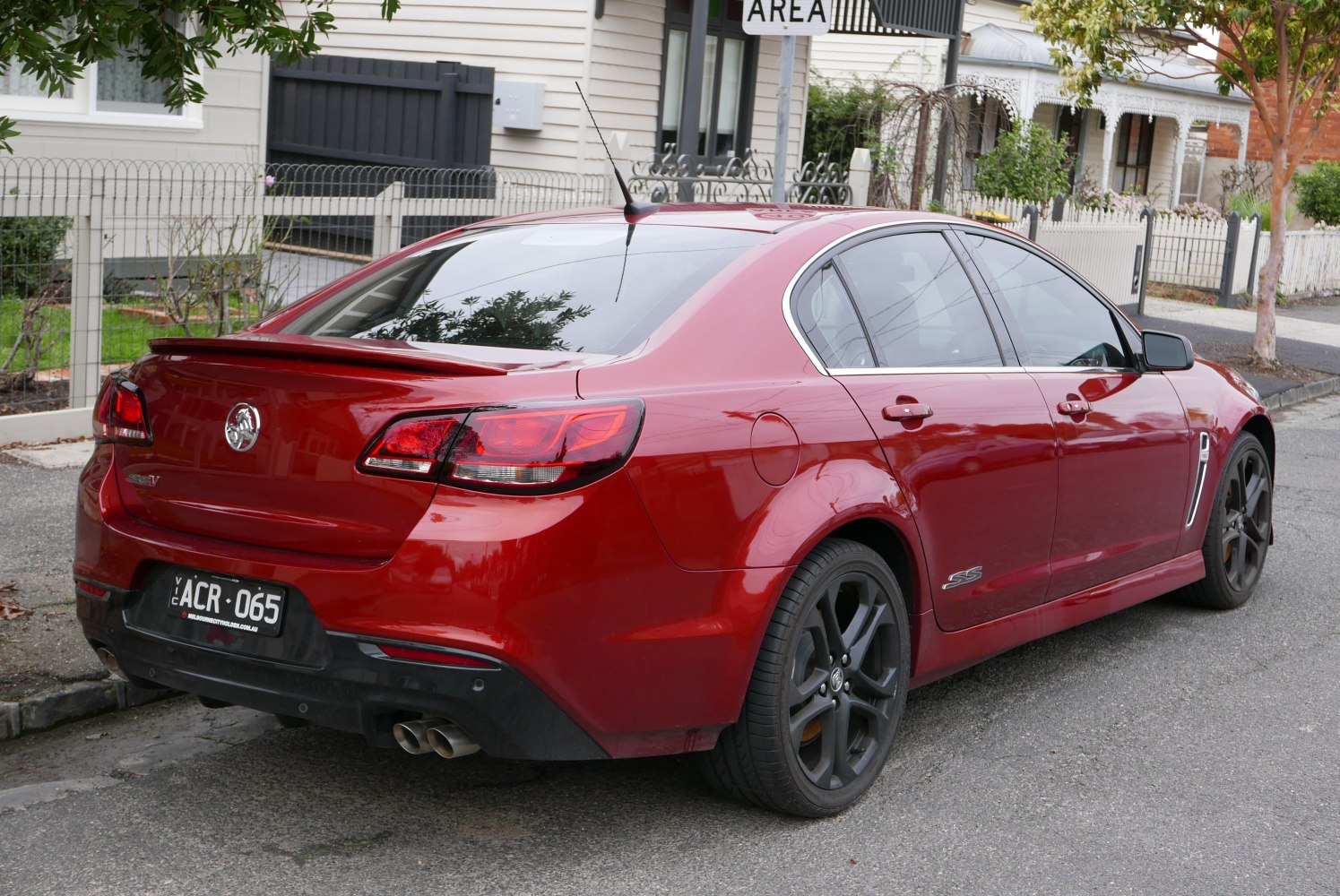 Red sedan with black rims, rear spoiler, tinted windows, and dual exhaust pipes