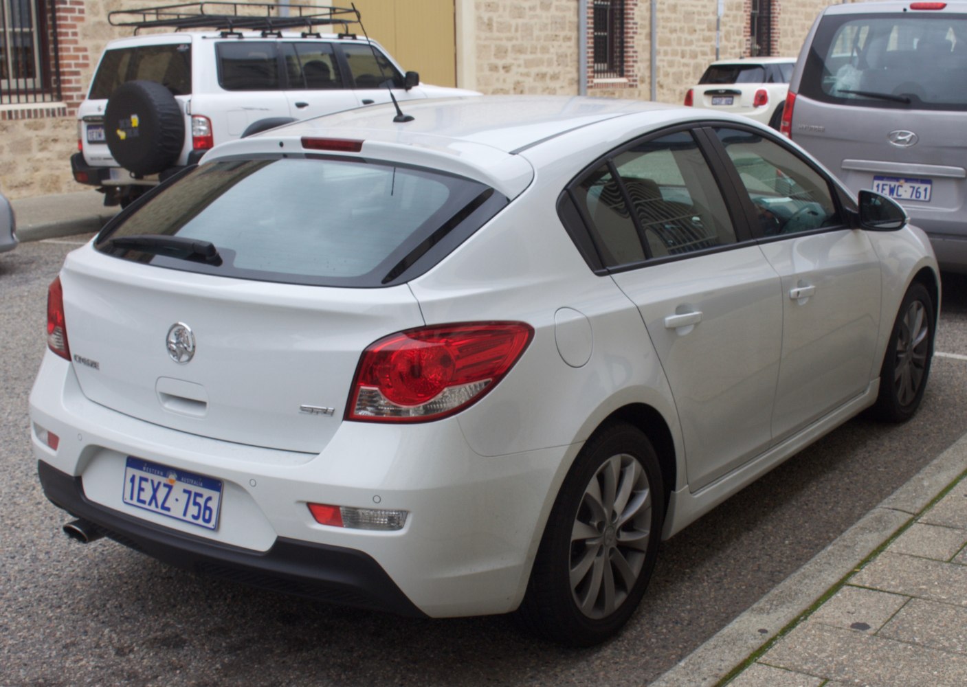 White hatchback rear-side with prominent rear lights and five doors