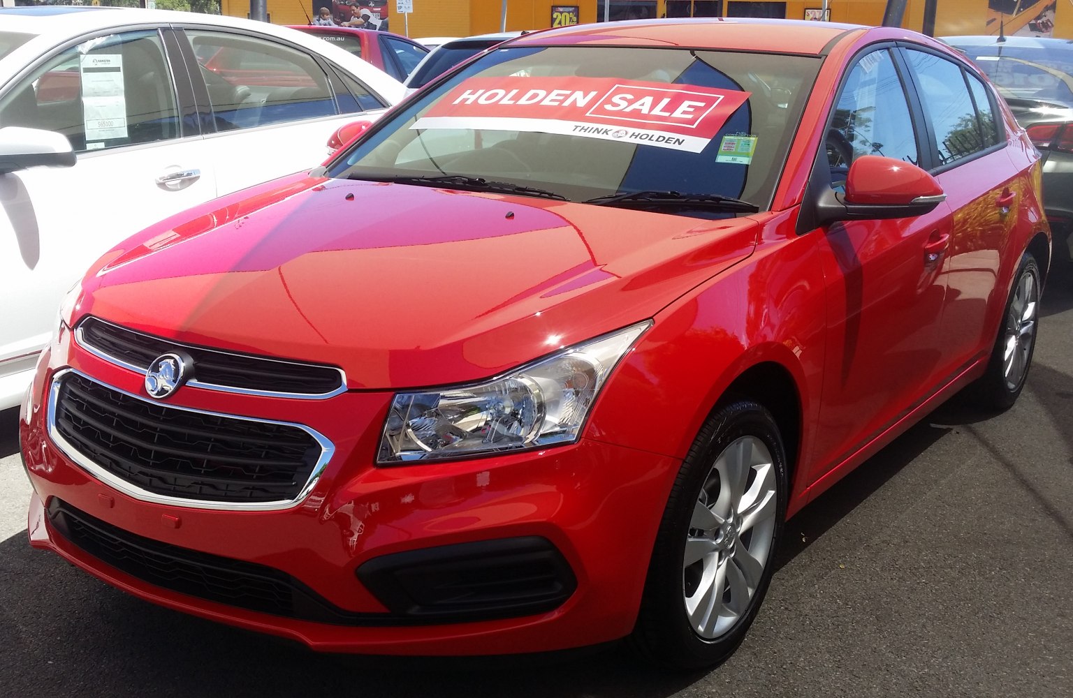 Red hatchback with Holden sale banner