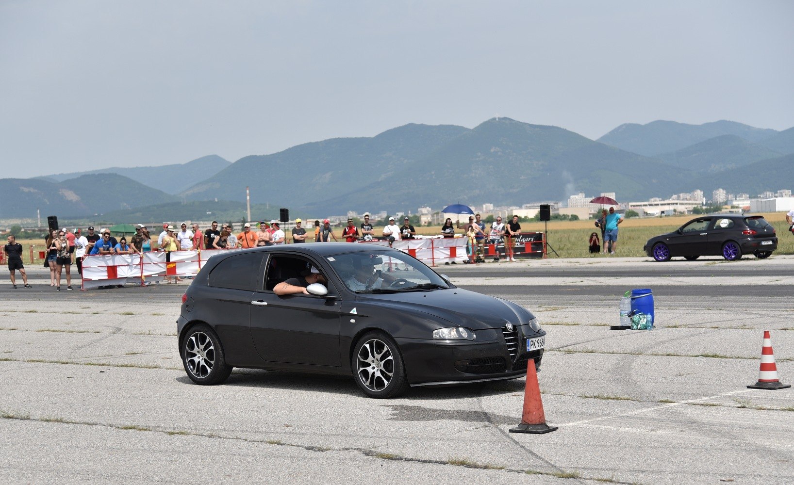 Black 3-door hatchback navigating cones at a car event