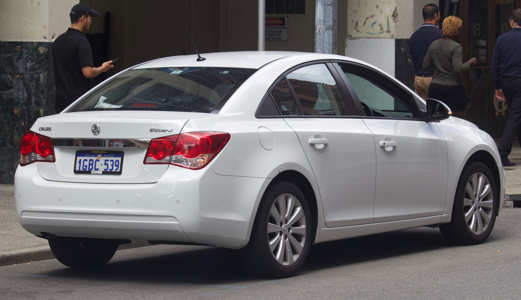 White sedan rear and side view with tail lights and four doors