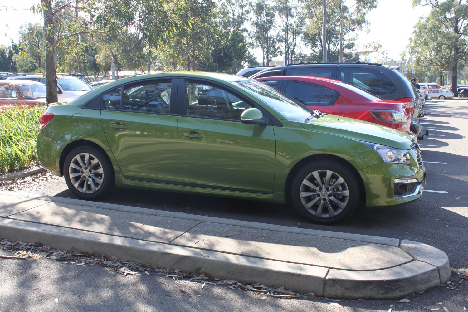 Side view of green sedan with alloy wheels and LED daytime running lights.