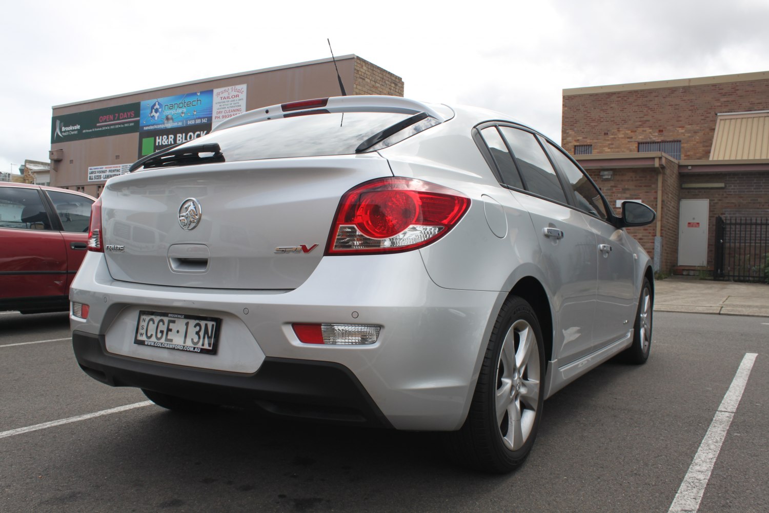 Rear-left angle view of a silver hatchback with sporty red taillights and rear windshield wiper