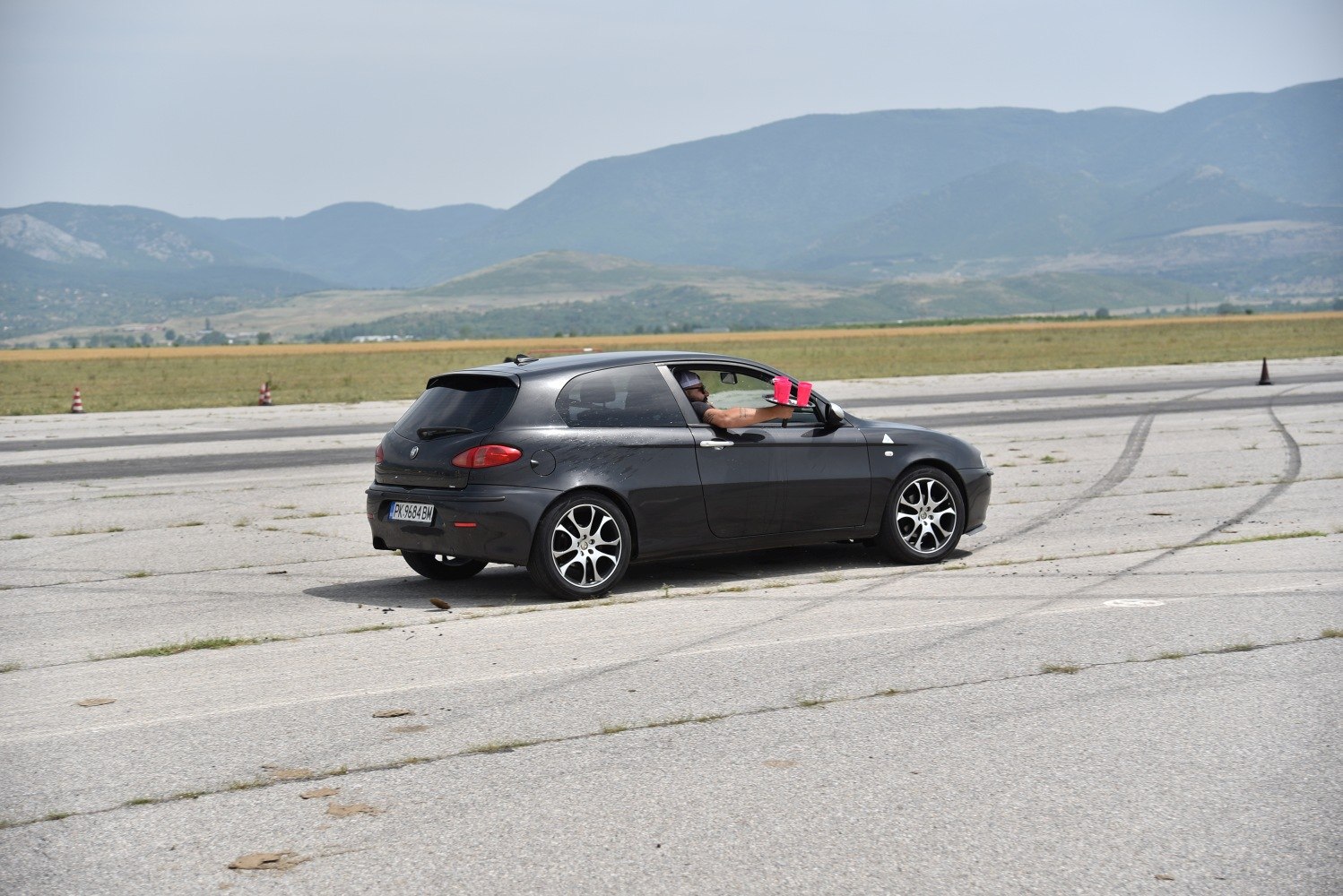 Black hatchback rear side view with sporty wheels on paved surface