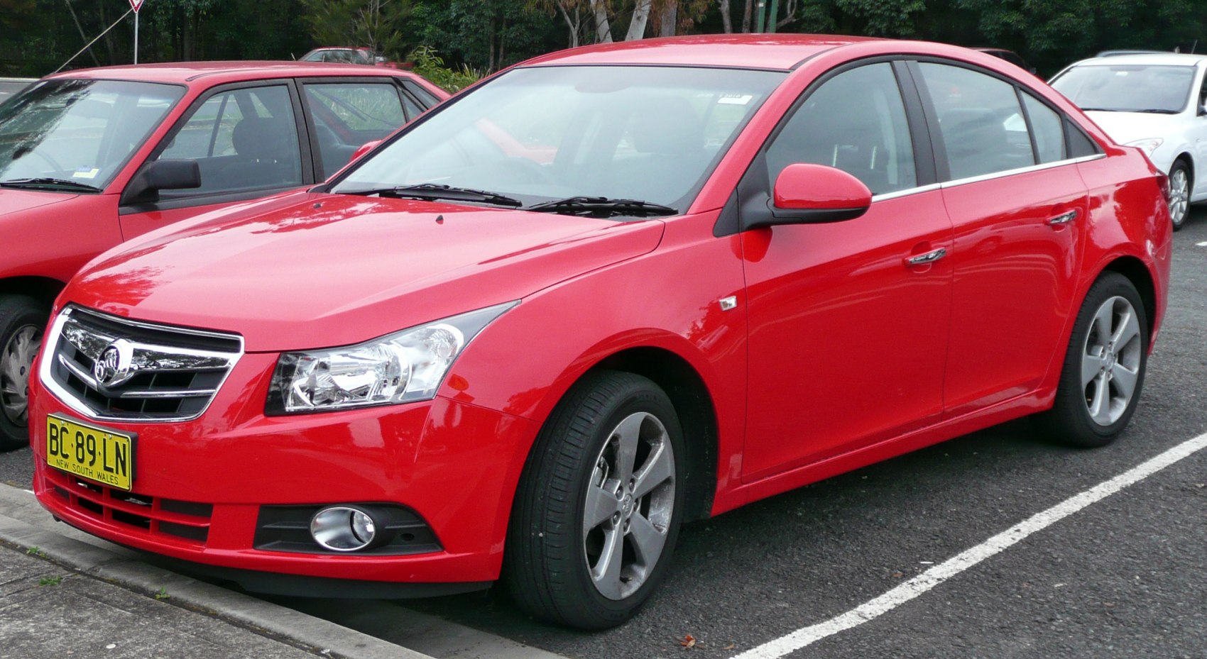 Red sedan with alloy wheels and chrome grille.