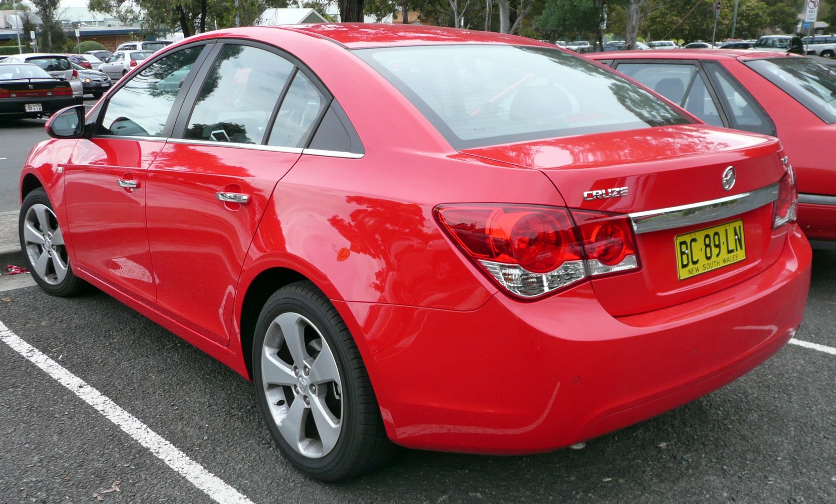 Red four-door sedan rear view with alloy wheels and distinct taillights