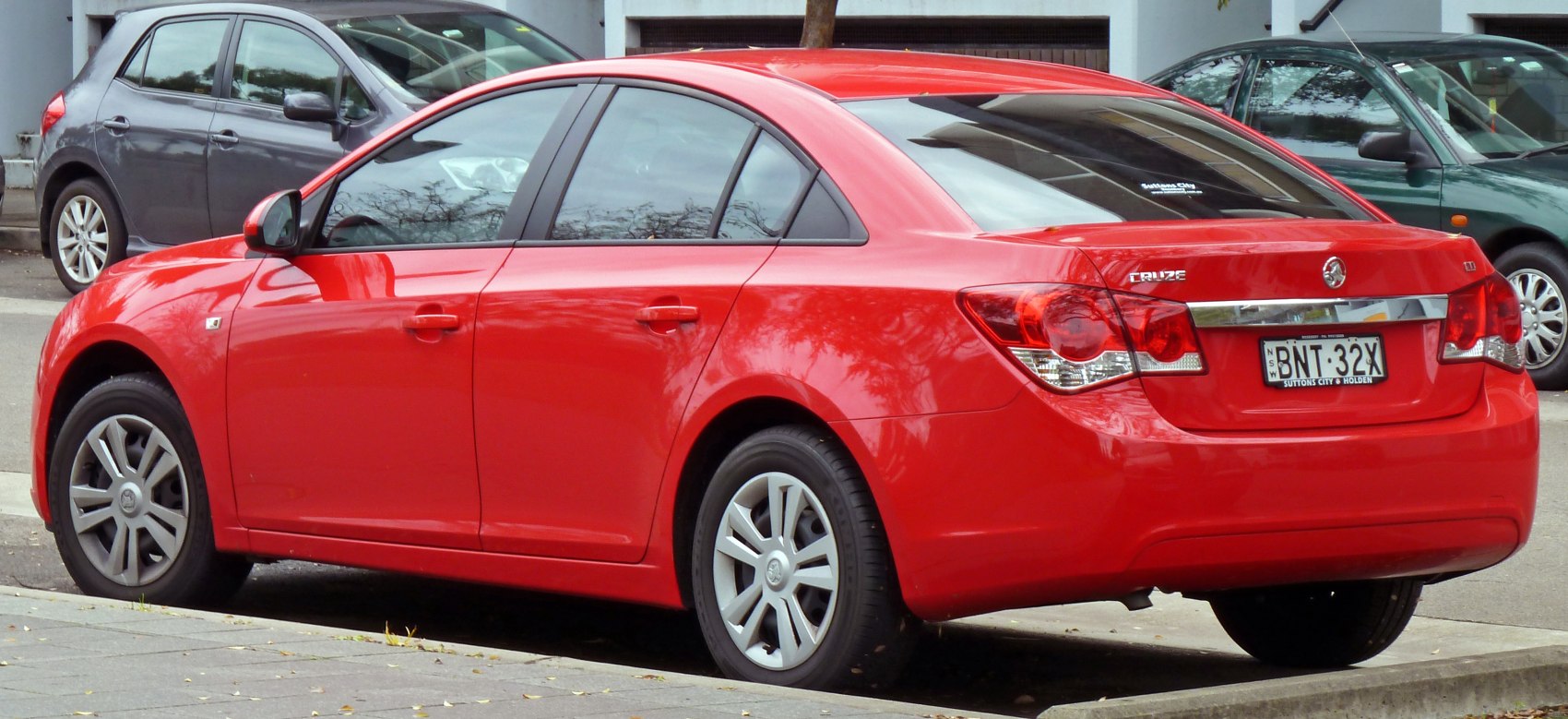 Rear-side view of a red compact sedan with unique tail lights and alloy wheels