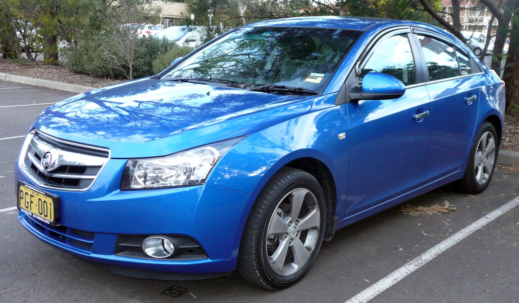 Blue sedan front-side view with headlights, alloy wheels, and fog lights