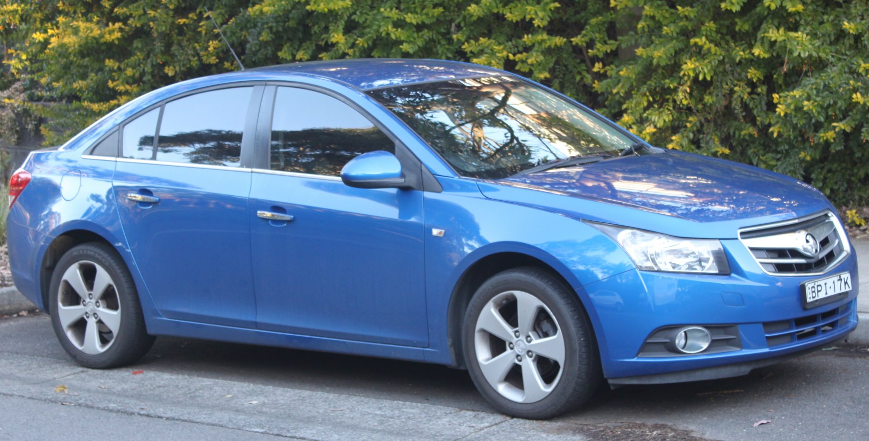 Blue sedan front side view, alloy wheels, fog lights, tinted windows