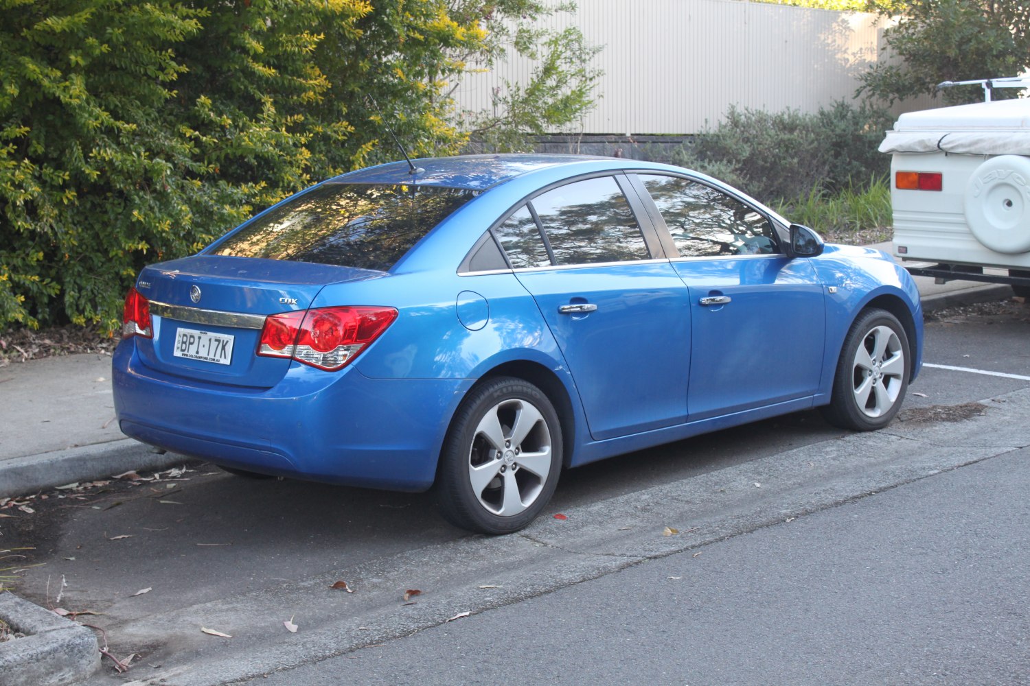 Blue compact sedan rear side view with alloy wheels and tinted windows