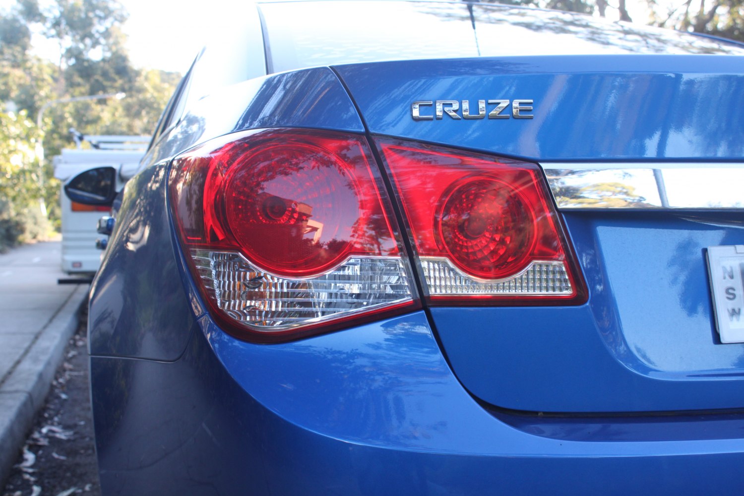 Close-up of a rear tail light and badge on a blue sedan